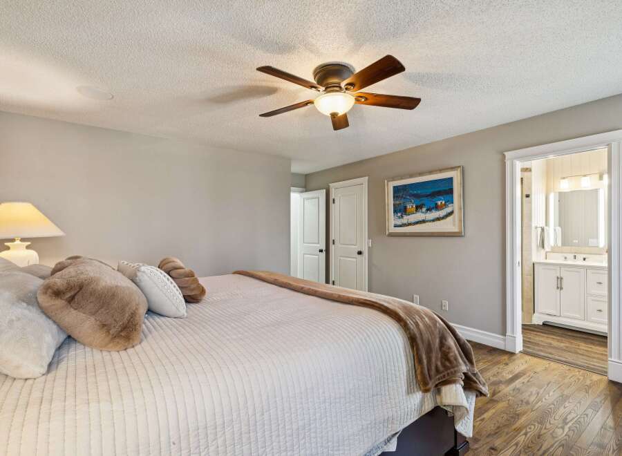 Step into this inviting bedroom, featuring a cozy bed adorned with plush pillows and a warm, inviting blanket.