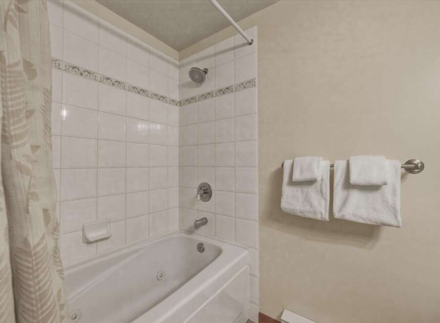 This inviting bathroom features a clean, modern design with white tile and a relaxing bathtub.