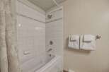 This inviting bathroom features a clean, modern design with white tile and a relaxing bathtub.