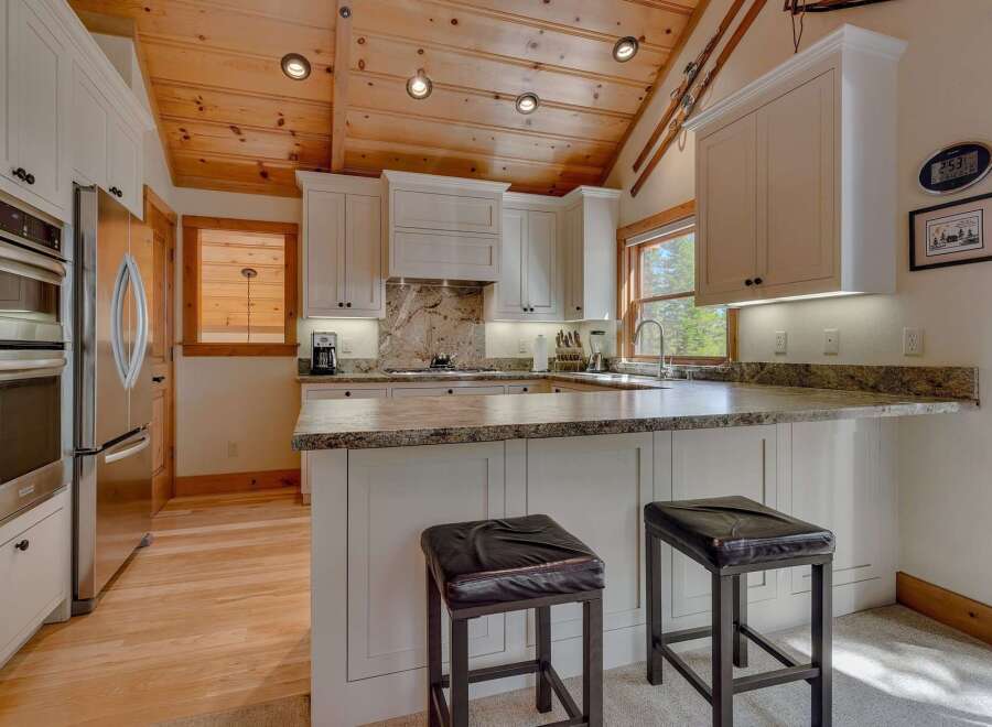 This stunning kitchen boasts a warm and inviting atmosphere with its wooden ceiling and ample natural light.