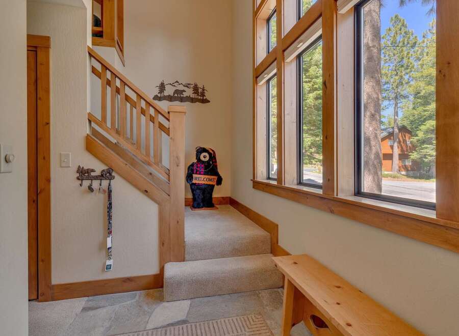 Step into this inviting entryway, featuring a charming staircase and a welcoming bear statue.