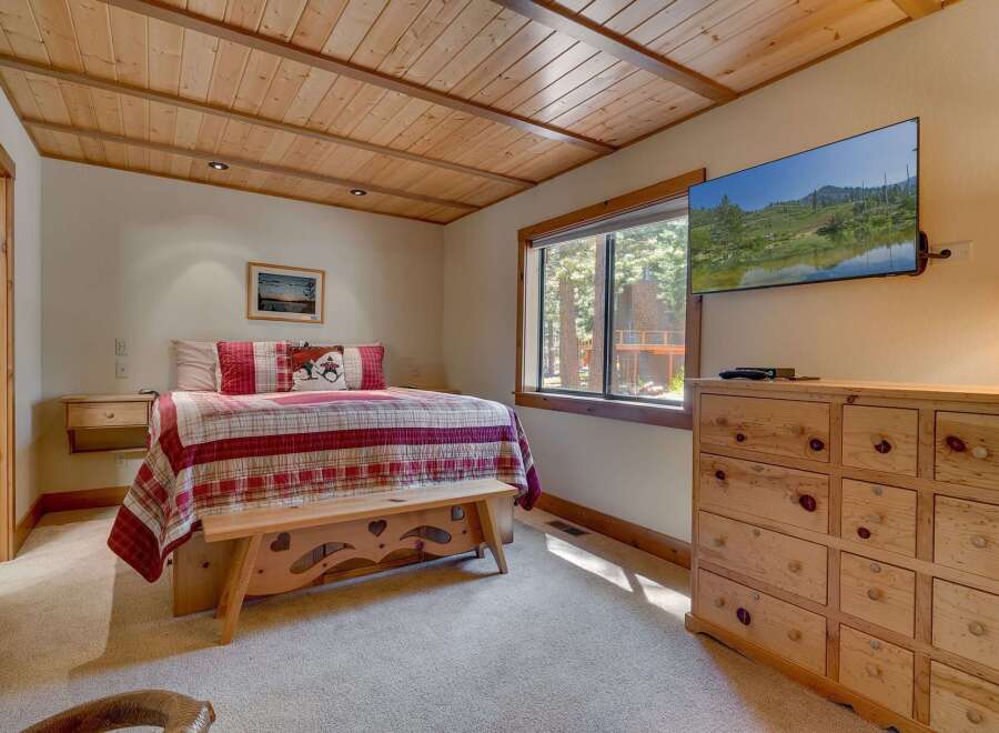 This cozy bedroom features a rustic wooden ceiling and a comfortable bed with a charming quilt.