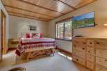 This cozy bedroom features a rustic wooden ceiling and a comfortable bed with a charming quilt.