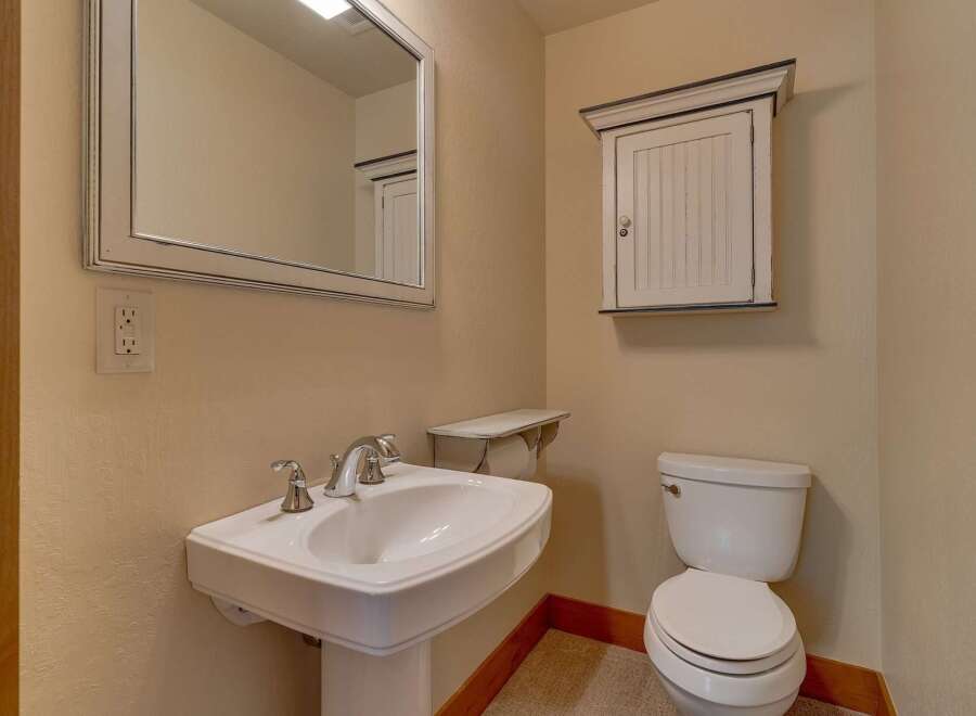 This charming bathroom features a classic pedestal sink, a pristine white toilet, and a stylish medicine cabinet.