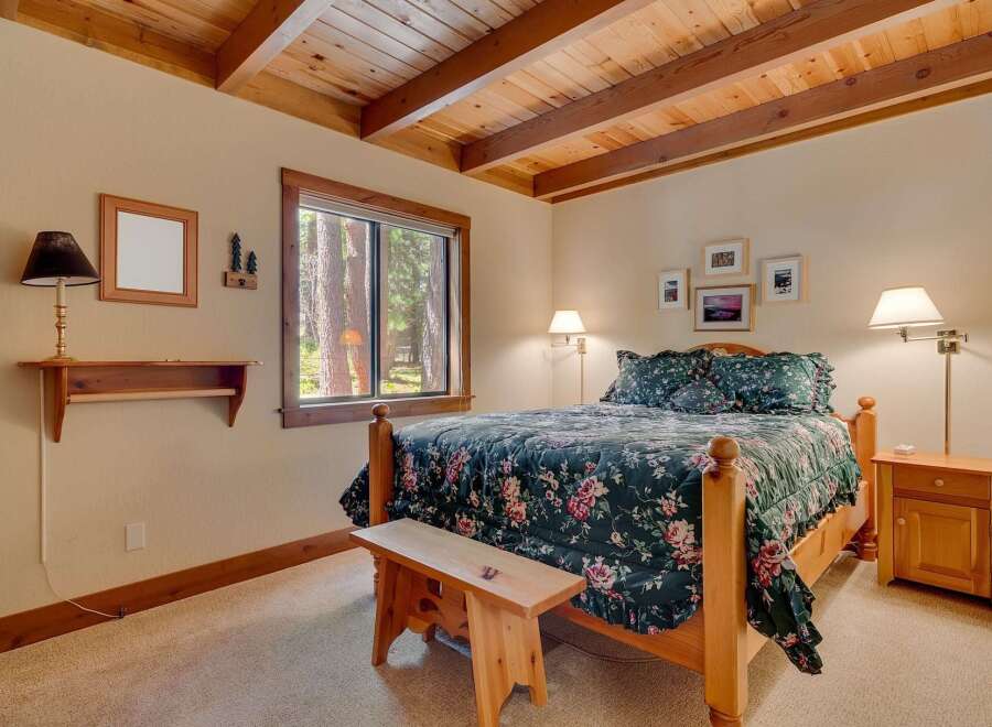 This charming bedroom features a cozy wooden bed frame and a beautiful floral comforter, creating a warm and inviting atmosphere.