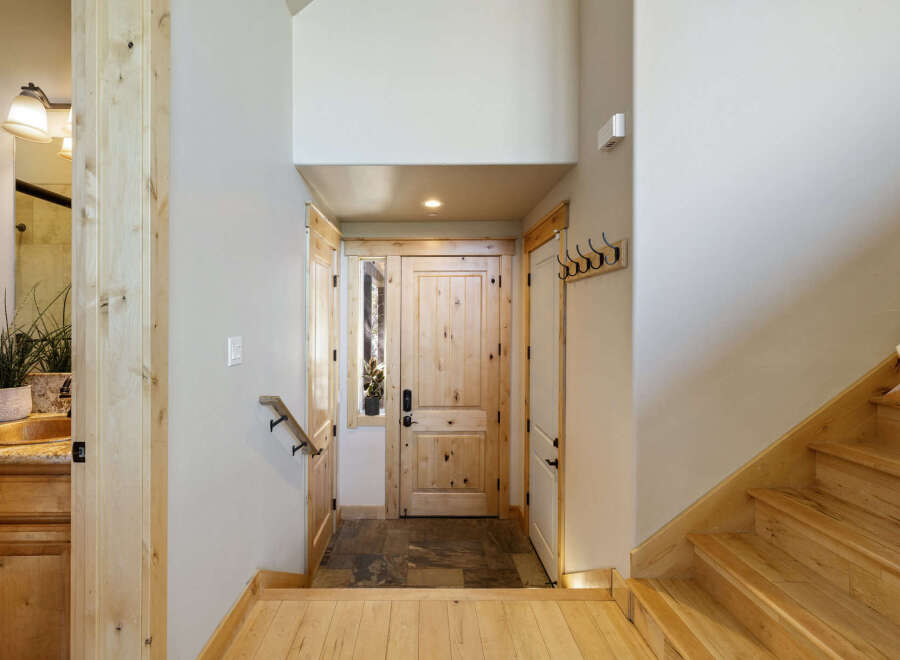 Step into this inviting entryway, showcasing a beautiful wooden door and a welcoming staircase.