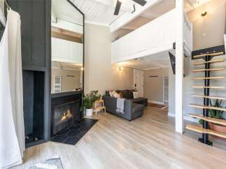 This stunning property boasts a modern living space with a cozy fireplace and a stylish staircase.