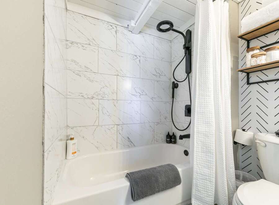 Step into a beautifully designed bathroom featuring a modern shower with sleek black fixtures and elegant marble-look tiles.