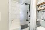 Step into a beautifully designed bathroom featuring a modern shower with sleek black fixtures and elegant marble-look tiles.
