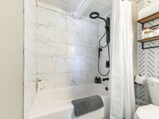 Step into a beautifully designed bathroom featuring a modern shower with sleek black fixtures and elegant marble-look tiles.