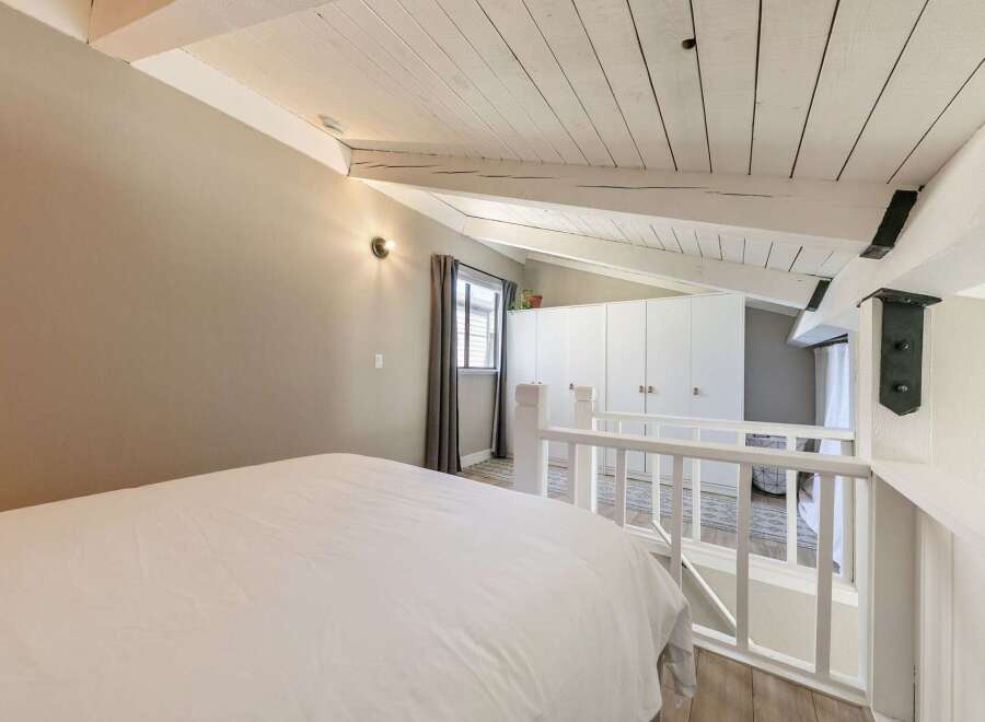 Discover the charm of this unique loft bedroom, featuring a cozy bed and a stylish white railing.
