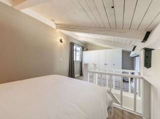 Discover the charm of this unique loft bedroom, featuring a cozy bed and a stylish white railing.