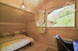 Discover the charm of this cozy bedroom, featuring warm wooden paneling and a bright, airy feel.