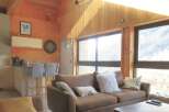 This stunning property boasts a cozy living room with a comfortable brown sofa and a charming wooden ceiling.