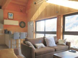 This stunning property boasts a cozy living room with a comfortable brown sofa and a charming wooden ceiling.