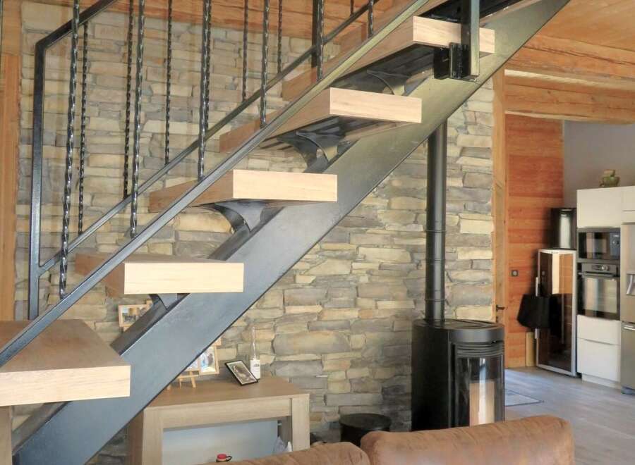 This stunning property boasts a modern staircase with a unique design, complemented by a rustic stone wall.