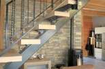 This stunning property boasts a modern staircase with a unique design, complemented by a rustic stone wall.