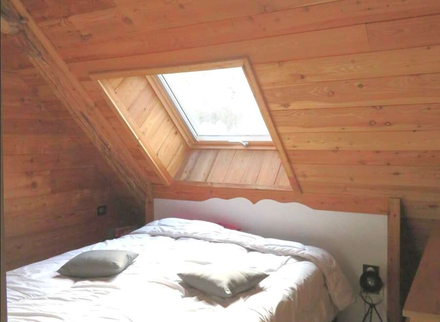 This cozy bedroom features a unique sloped ceiling with a skylight, creating a bright and airy atmosphere.