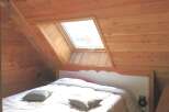 This cozy bedroom features a unique sloped ceiling with a skylight, creating a bright and airy atmosphere.