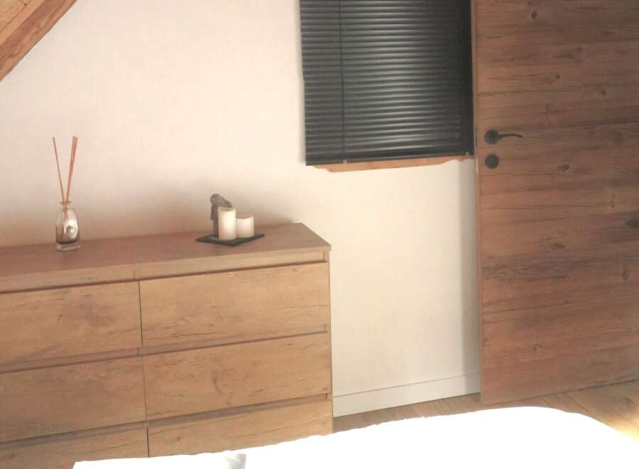 This charming bedroom features a beautiful wooden dresser, perfect for storage and adding a touch of rustic elegance.