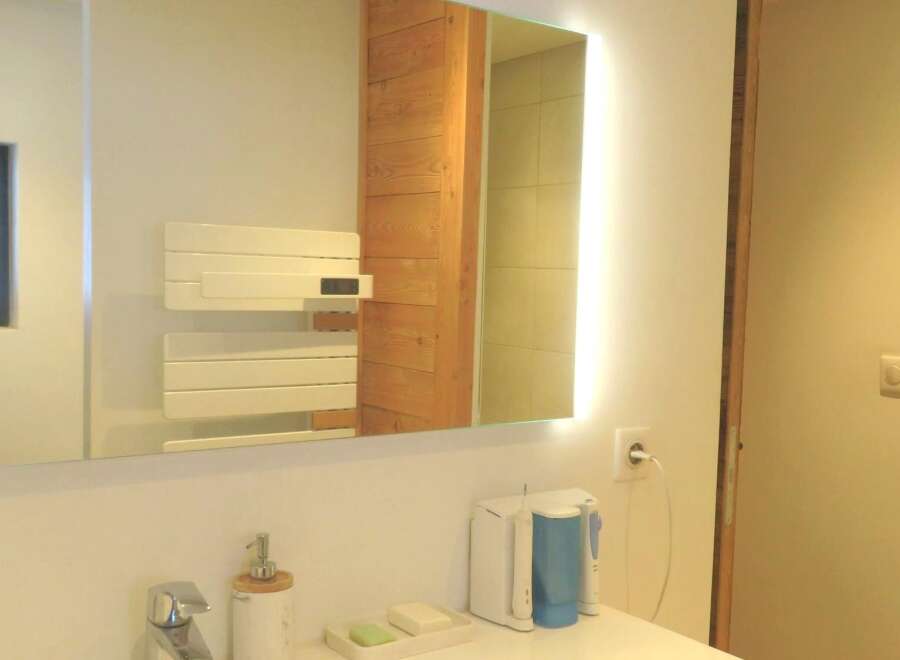 Step into this modern bathroom, featuring a sleek, illuminated mirror that enhances the space.