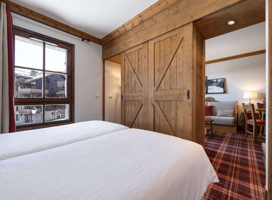 Experience the charm of this cozy bedroom featuring a rustic wooden sliding door that leads to a living area.