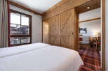 Experience the charm of this cozy bedroom featuring a rustic wooden sliding door that leads to a living area.