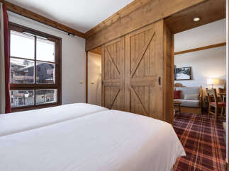 Experience the charm of this cozy bedroom featuring a rustic wooden sliding door that leads to a living area.