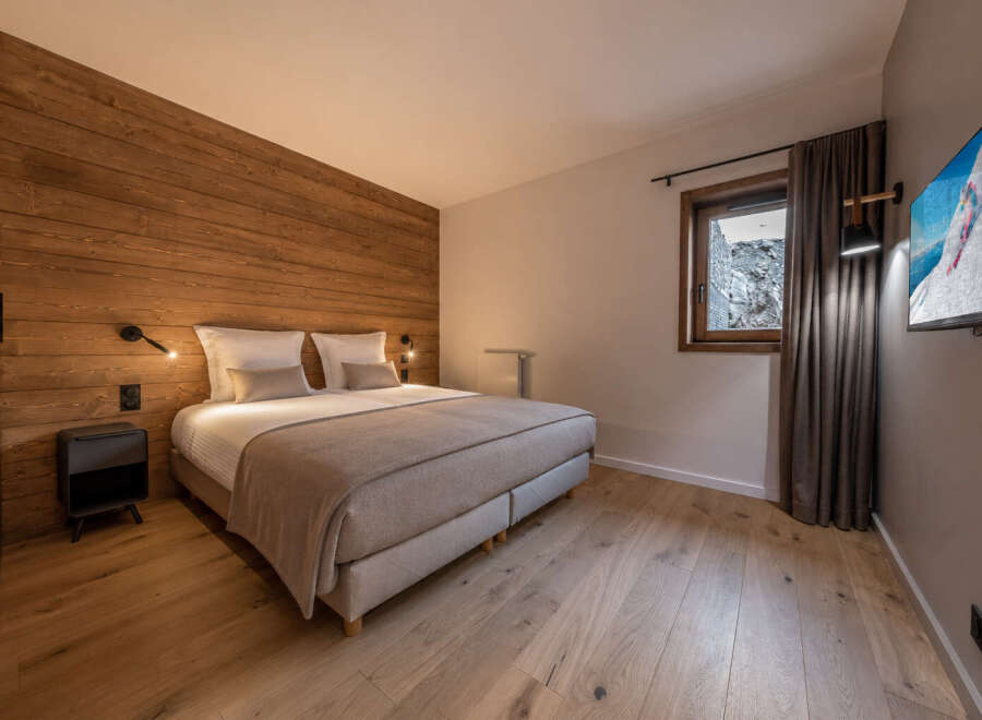 Experience luxury in this stunning bedroom featuring a warm wooden accent wall and elegant design.