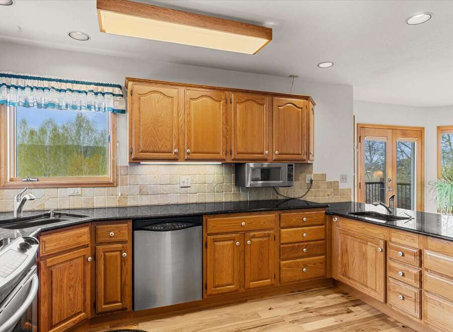 This stunning kitchen boasts beautiful wooden cabinetry and sleek black countertops, creating a warm and inviting atmosphere.