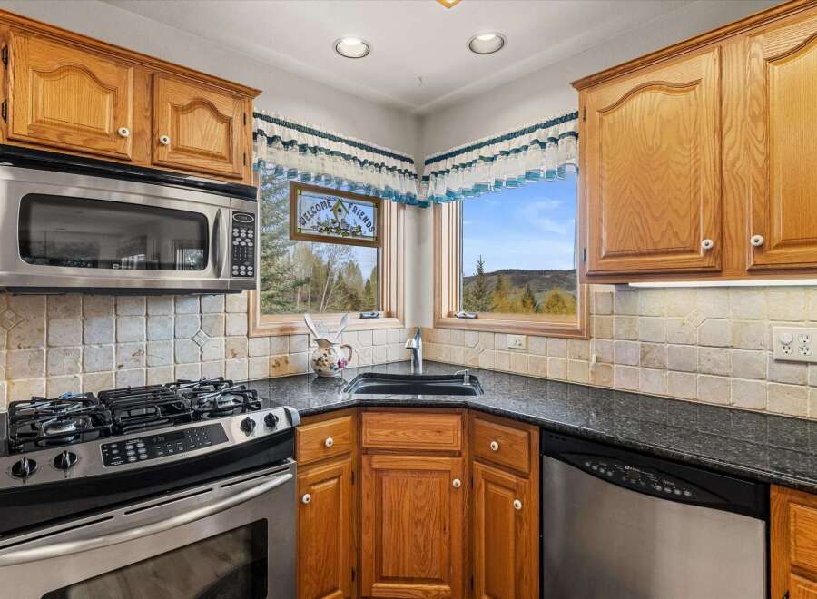 This stunning kitchen boasts beautiful wooden cabinetry and a sleek black countertop, creating a warm and inviting atmosphere.
