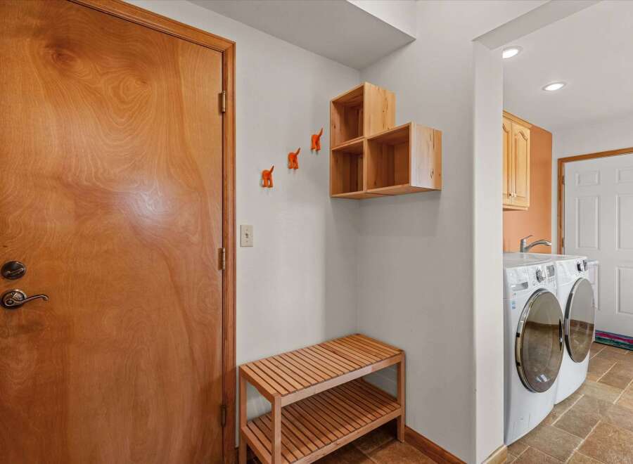 Step into this inviting entryway, featuring a stylish wooden door and a convenient bench for your everyday needs.