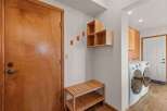 Step into this inviting entryway, featuring a stylish wooden door and a convenient bench for your everyday needs.