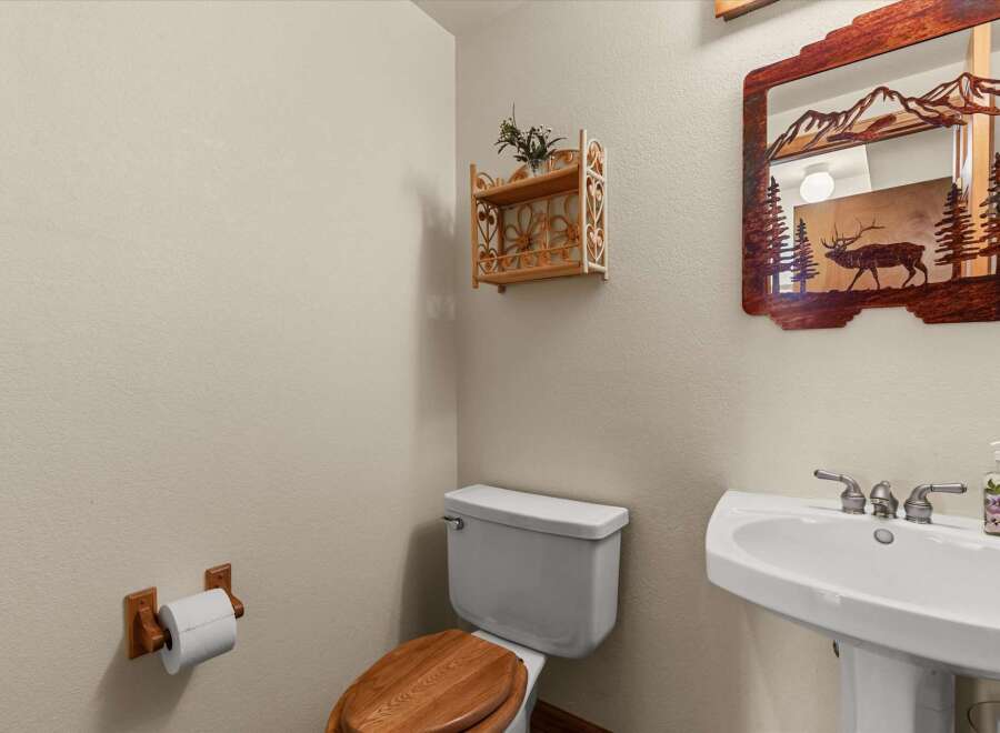This charming bathroom features a unique wooden mirror with a mountain and elk design, adding a touch of rustic elegance.