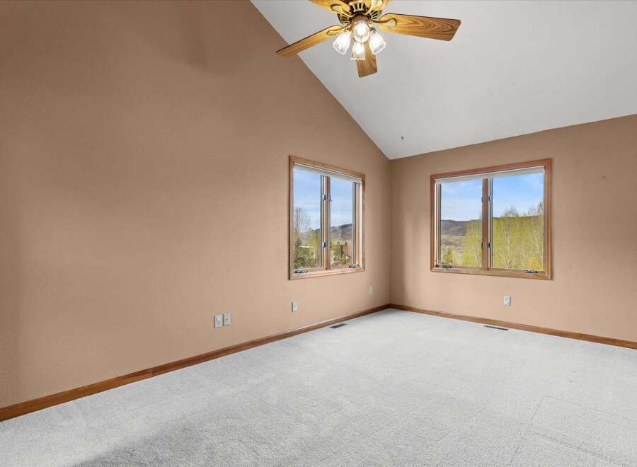 Discover the charm of this inviting bedroom, featuring a vaulted ceiling and ample natural light streaming through the windows.