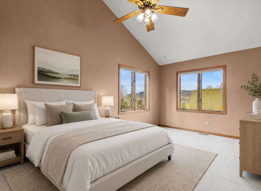 This stunning bedroom boasts a serene ambiance with its neutral color palette and vaulted ceilings.