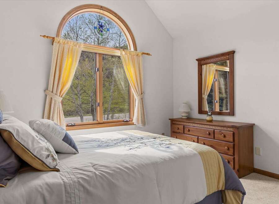 This charming bedroom features a large arched window that offers stunning views of the surrounding nature.