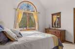This charming bedroom features a large arched window that offers stunning views of the surrounding nature.