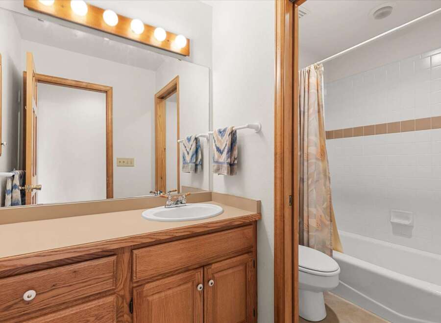 This bathroom features a classic design with a wooden vanity and a large mirror, creating a warm and inviting atmosphere.