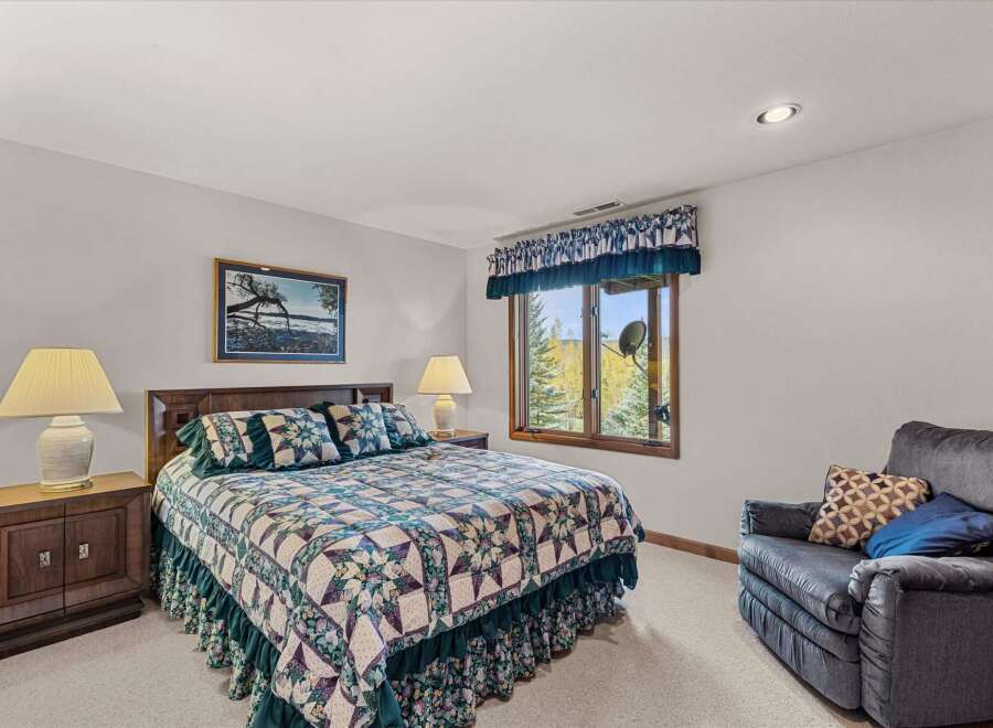 This cozy bedroom features a comfortable bed adorned with a beautiful quilt and matching pillows.