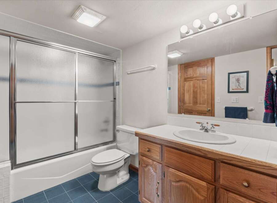 Step into this inviting bathroom, featuring a well-lit vanity area and a convenient shower-tub combo.