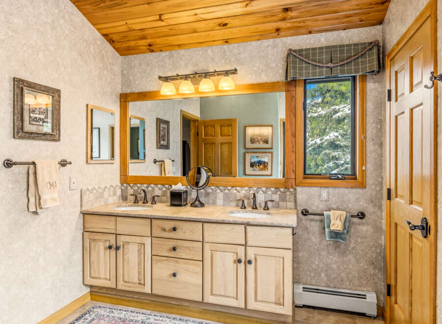 This beautiful bathroom features a wooden ceiling and a large vanity with double sinks.