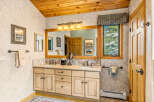 This beautiful bathroom features a wooden ceiling and a large vanity with double sinks.