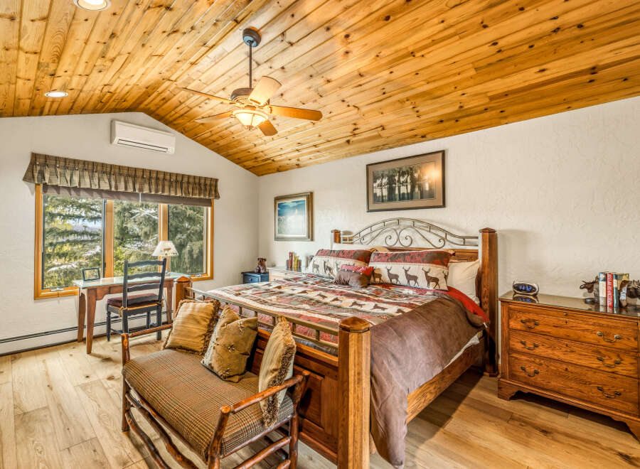 Step into a cozy bedroom retreat featuring a stunning wooden ceiling and warm, inviting ambiance.