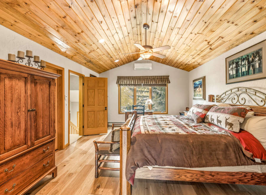 This stunning bedroom boasts a rustic charm with its wooden ceiling and flooring, creating a warm and inviting atmosphere.