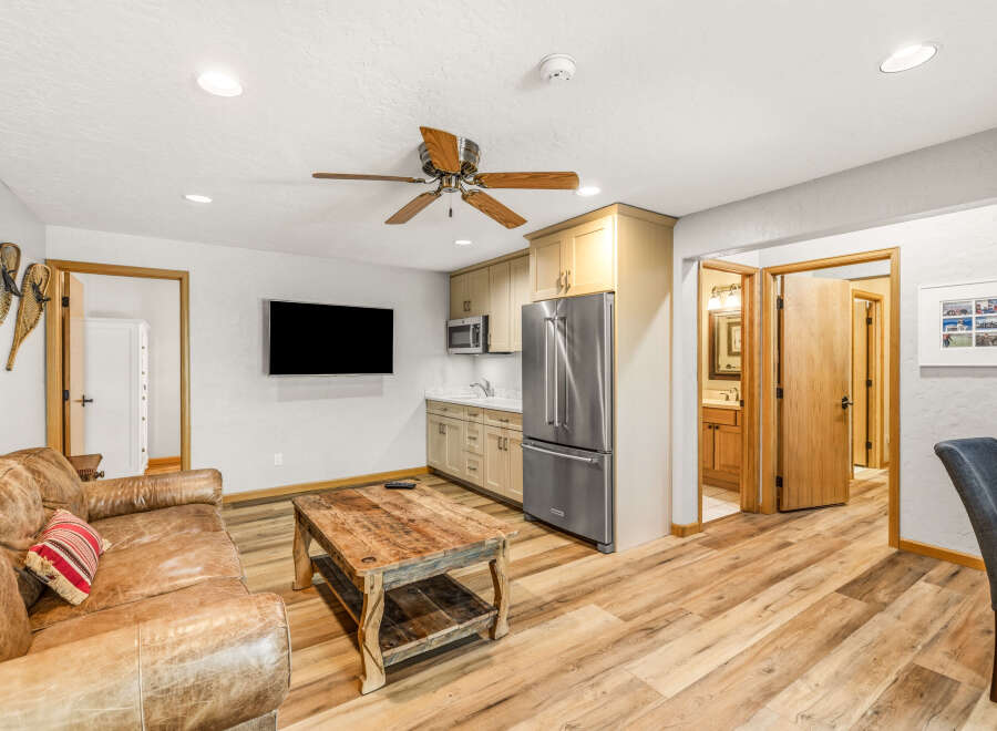 This inviting living space features a cozy leather sofa and a rustic wooden coffee table, perfect for relaxing.