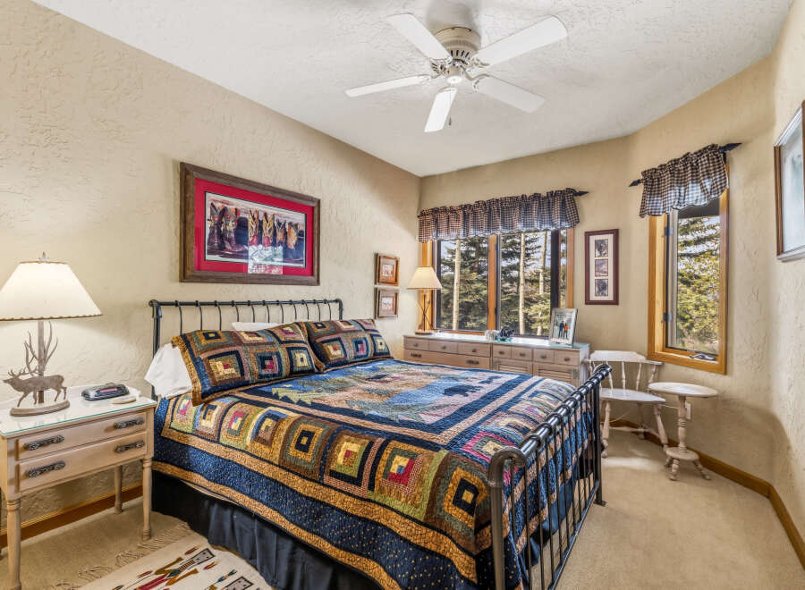 This cozy bedroom features a comfortable bed adorned with a colorful quilt, perfect for a relaxing retreat.