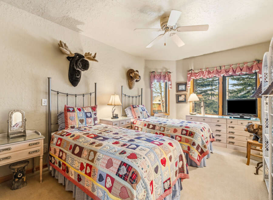 This charming bedroom features two twin beds adorned with cozy, patchwork quilts, perfect for a guest room or a shared space.