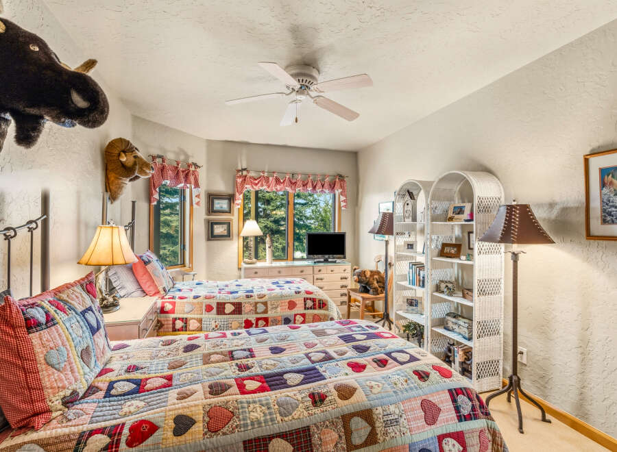 This charming bedroom features two cozy beds adorned with colorful quilts, perfect for a comfortable stay.