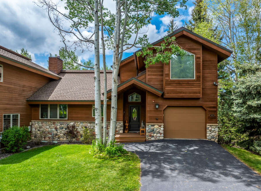 This stunning property boasts a beautiful exterior with wood siding and a stone foundation, offering a warm and inviting aesthetic.